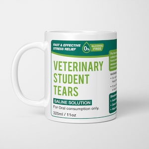 May include: A white ceramic mug featuring a green and white label that reads VETERINARY STUDENT TEARS, SALINE SOLUTION, FAST & EFFECTIVE STRESS RELIEF, 0% ALCOHOL FREE, For Oral consumption only, and 325ml / 11oz, with additional warning and direction text.