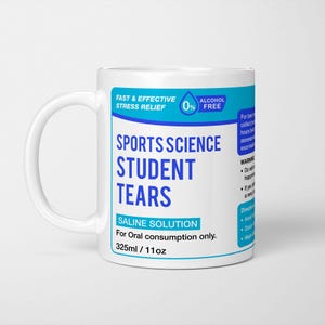 May include: A white ceramic mug featuring a blue and white label that reads Sports Science Student Tears, Saline Solution, For Oral consumption only, 325ml / 11oz, Fast & Effective Stress Relief, 0% Alcohol Free, and additional warning text.