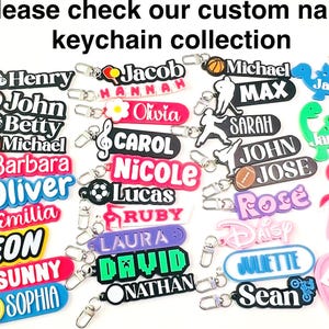 May include: A collection of custom name keychains in various colors and shapes. Keychains include names like "Henry", "Jacob", "Michael", and "Sarah". Some keychains feature sports-themed designs, while others have cartoon characters.