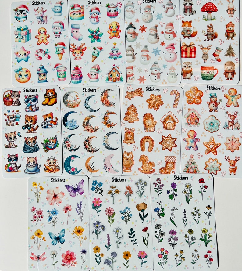 May include: A collection of sticker sheets featuring various designs. The sheets include stickers with winter holiday themes like snowmen and gingerbread men, along with floral and celestial designs. Each sheet is labeled with the word "Stickers".