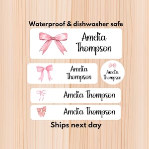 May include: White rectangular labels featuring pink bow illustrations and the name "Amelia Thompson" in a script font. The text "Waterproof & dishwasher safe" is at the top. The text "Ships next day" is at the bottom.