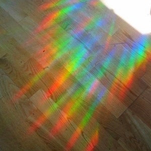 May include: A rainbow prism effect cast on a wooden floor, creating a colorful pattern of light.