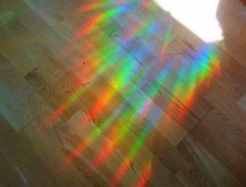 May include: A rainbow prism effect cast on a wooden floor, creating a colorful pattern of light.
