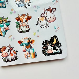 May include: A sheet of stickers featuring cartoon cows in various poses. Some cows wear sunglasses, while others are adorned with flowers or hold drinks. The stickers have a white background with colorful accents and are suitable for crafts or decorating.