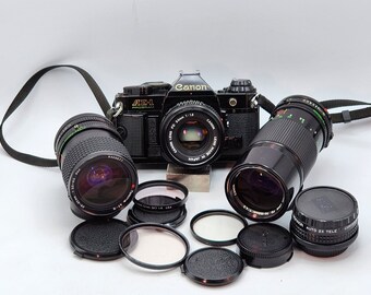 Canon AE-1 SLR Film Camera Black w/ Canon FD 50mm f1.8, Canon 70mm-150mm f4.5, Tokina At-x 28-85mm 1:3.5-4.5 Lens, 2x Tele Converter