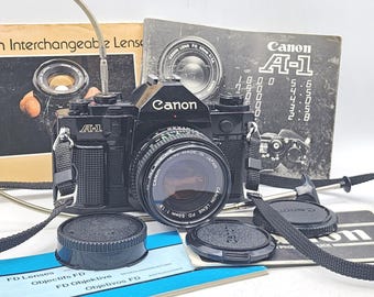 Canon A-1 35 mm 一眼レフフィルムカメラ、Canon FD 50 mm f/1.8 レンズ、キャップ、フィルター、説明書