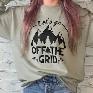 May include: A sage green sweatshirt with a black graphic print of mountains, trees, and the text "Let's go off the grid".