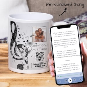 Könnte beinhalten: Eine weiße Keramiktasse mit einem schwarz-weißen Musiknoten-Design. Die Tasse zeigt ein Foto eines Paares und einen QR-Code mit dem Text "Um unseren Song zu hören, QR-CODE SCANNEN". Der Text "Jack & Oliver UNSER LIED" ist ebenfalls auf der Tasse.