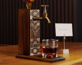 Può includere: Un distributore di liquore in legno con un rubinetto in ottone e un design a testa di cervo. Il distributore ha una targhetta personalizzata con il nome "Peter Miller".
