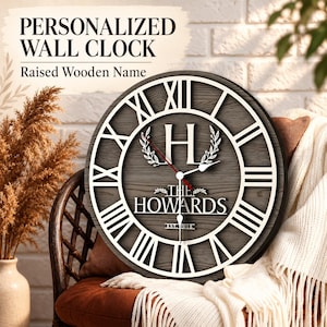 Könnte beinhalten: Eine runde Wanduhr mit dunkelgrauem Holzmaserungshintergrund und weißen römischen Ziffern. In der Mitte befinden sich ein großer weißer Buchstabe H, der Text THE HOWARDS und EST. 2018. Sie hat weiße Stunden- und Minutenzeiger sowie einen roten Sekundenzeiger.