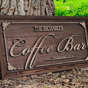 Pode incluir: Uma placa de madeira marrom escura com uma inscrição dourada que diz "The Richard's Coffee Bar Established 2018".