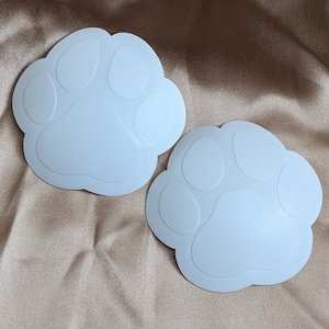 May include: Two white paw print shaped stickers. The stickers are made of a smooth, matte material.