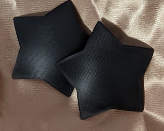 May include: Two black star-shaped fabric patches. The patches are made of a soft, textured material.