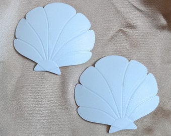 May include: Two white seashell-shaped decorations with a raised, textured design.