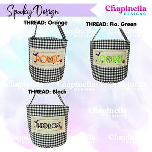 May include: Three black and white gingham fabric baskets with handles. Each features a rectangular cream-colored patch embroidered with names in orange, fluorescent green, or black thread, accented with small spiderweb and bat motifs.