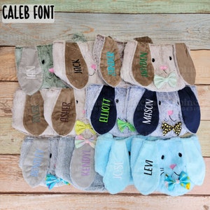 Puede incluir: Una colecci&oacute;n de sombreros de orejas de conejo de felpa en varios colores, cada uno bordado con un nombre. Los sombreros presentan orejas, lazos y detalles faciales de diferentes colores. El texto "CALEB FONT" est&aacute; en la parte superior izquierda.