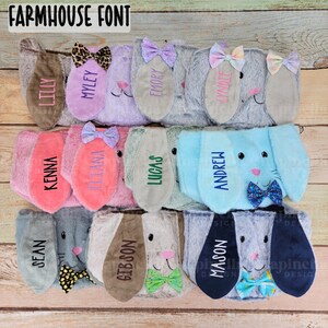 Puede incluir: Una colecci&oacute;n de diademas de orejas de conejo de felpa en varios colores, cada una bordada con un nombre. Las diademas presentan lazos y forros de orejas de diferentes colores. El texto "FARMHOUSE FONT" est&aacute; en la parte superior de la imagen.