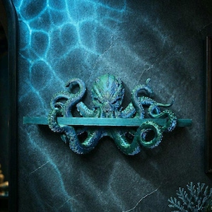 May include: A wall-mounted shelf featuring a sculpted octopus with textured, swirling tentacles in shades of deep blue and green. The octopus head is centred above a horizontal shelf board, with tentacles extending outward and curling around the edges.