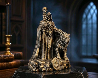 Puede incluir: Una figura de resina dorada y negra que representa a un esqueleto encapuchado con túnica que sostiene un bastón rematado con una calavera, acompañado de una criatura lobuna. La base presenta varias calaveras y un escudo sobre una plataforma hexagonal.