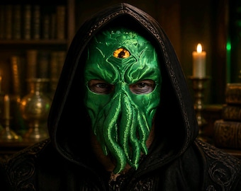 Puede incluir: Una máscara de color verde brillante con un diseño facial texturizado de tentáculos y un tercer ojo prominente en el centro de la frente. La máscara se lleva bajo una prenda oscura con capucha, cubriendo la nariz y la boca con tentáculos.