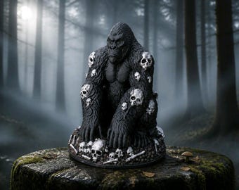 Puede incluir: Una figura de gorila negro con múltiples calaveras blancas incrustadas en su pelaje, descansando sobre una base cubierta por un montón de calaveras y huesos blancos. El gorila está sentado, inclinado hacia adelante con las manos en el suelo.