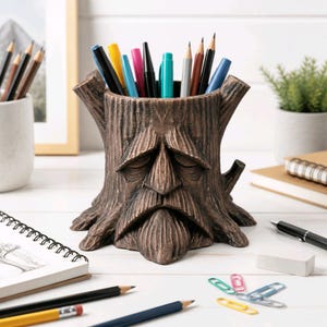 May include: A brown tree stump pencil holder featuring a sculpted face with closed eyes and a beard. The cylindrical container is filled with various colored pens and pencils, showcasing a textured bark finish and a wide, stable base.