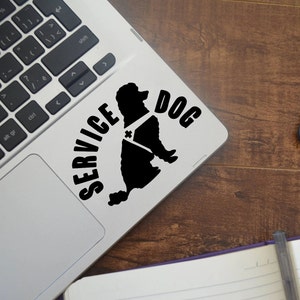 May include: A black and white sticker of a poodle with a service dog vest on a silver laptop. The sticker says "SERVICE DOG" in black text.