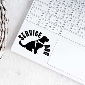 May include: Black and white silhouette of a service dog wearing a harness with the words "SERVICE DOG" in a semi-circle above the dog. The image is on a white laptop.