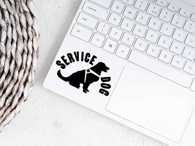 May include: Black and white silhouette of a service dog wearing a harness with the words "SERVICE DOG" in a semi-circle above the dog. The image is on a white laptop.