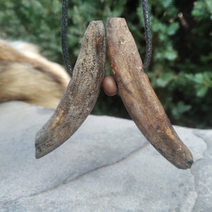 May include: A brown antler pendant with a brown bead on a black cord.