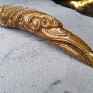 May include: A hand-carved wooden bird sculpture with intricate details. The bird has a long beak and a detailed head with a large eye. The sculpture is made of light brown wood and has a smooth finish.