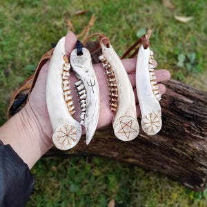 Roe deer bone jewelry with a detailed Nordic pattern lying on a palm