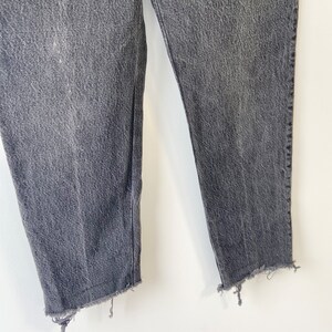 May include: A pair of dark gray denim jeans with a frayed hem.