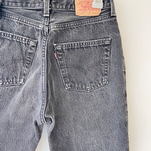 May include: A pair of dark gray denim jeans with a Levi Strauss & Co. red tab on the back pocket.