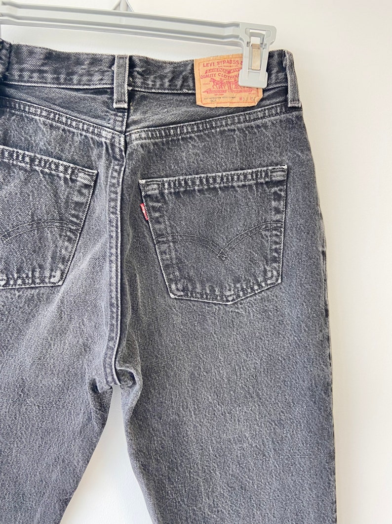 May include: A pair of dark gray denim jeans with a Levi Strauss & Co. red tab on the back pocket.