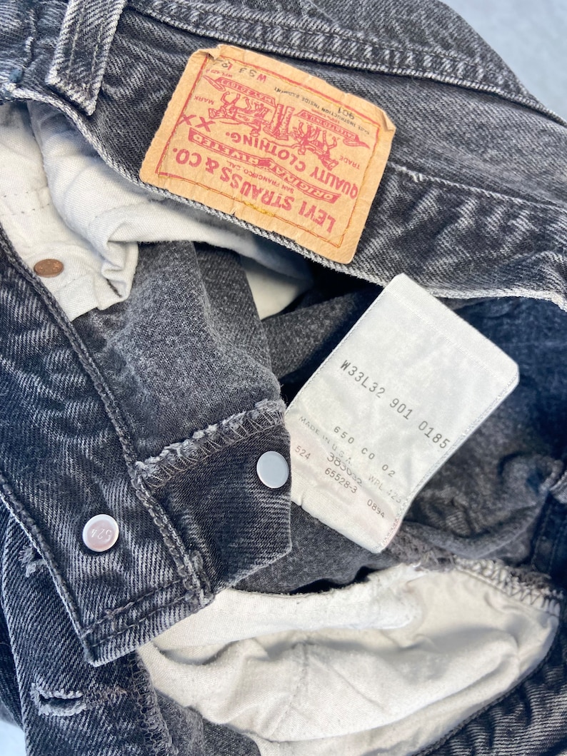 May include: A pair of black denim jeans with a Levi Strauss & Co. label and a size tag that reads "W33L32 901 0185".