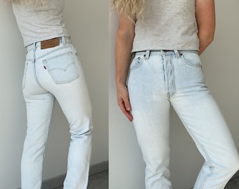 May include: Light blue denim jeans with a straight leg fit. The jeans have a classic five-pocket style and a button fly.