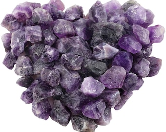 May include: A heart-shaped arrangement of raw amethyst crystals. The crystals vary in shades of purple, from light lavender to deep violet, with some areas appearing nearly black. The rough-cut stones are clustered closely together.