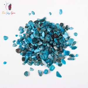 May include: A pile of blue and green apatite chips on a white background. The chips are various sizes and shapes.