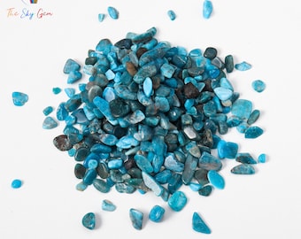 May include: A pile of blue and green apatite chips on a white background. The chips are various sizes and shapes.