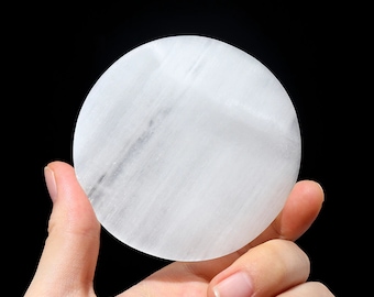 May include: A white selenite charging plate, a smooth, round disc with a slightly textured surface.