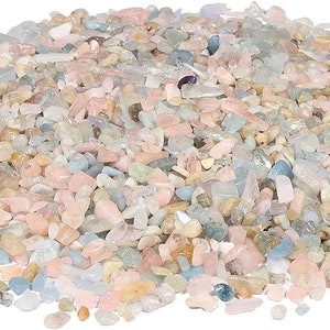 Op de afbeelding: Een verzameling kleine, gepolijste edelstenen in pasteltinten. De stenen vertonen een reeks kleuren, waaronder roze, blauw en crème, met zowel transparante als ondoorzichtige afwerkingen. Deze decoratieve stenen zijn geschikt voor knutselen en sieraden maken.