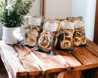 Könnte beinhalten: Vier kleine Beutel mit getrockneten Früchten und Kräutern, die mit Schnur gebunden sind. Die Beutel sind mit dem Text "Gift & Give" und den Namen verschiedener Potpourri-Mischungen beschriftet: "Apple Pie Potpourri", "Christmas Tree", "Holiday Potpourri" und "Fall '22".