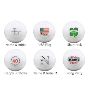 May include: Six white ping pong balls with different designs. The designs include a name and initial, a USA flag, a shamrock, a happy birthday message with a number 40, a name and initial, and a pong party message.
