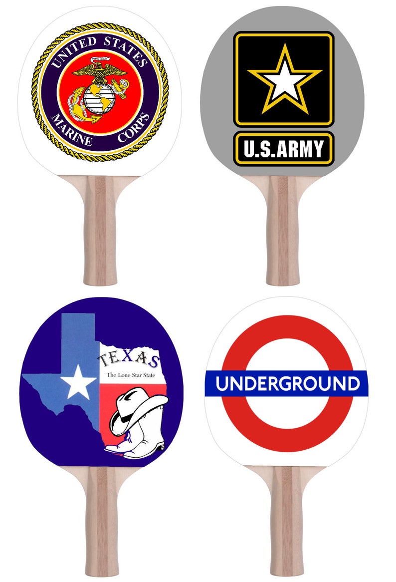 May include: Four different designs of table tennis paddles. The first paddle has a white background with a gold and blue United States Marine Corps logo. The second paddle has a gray background with a black star and the text "U.S. ARMY". The third paddle has a blue background with a white outline of the state of Texas and the text "TEXAS The Lone Star State". The fourth paddle has a white background with a red circle and the text "UNDERGROUND" in blue.