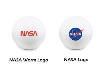 May include: Two white ping pong balls with different NASA logos. One ball has the red "NASA" worm logo. The other ball has the blue and red NASA logo with a red star.