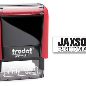 May include: Red and black self-inking stamp with the text "trodat printy 4911" and "printy Clothing Marker". The stamp is designed to print the name "JACKSON REEDMAN" in black ink.