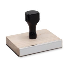 May include: A wooden stamp with a black handle. The stamp has a white surface with a silver border.