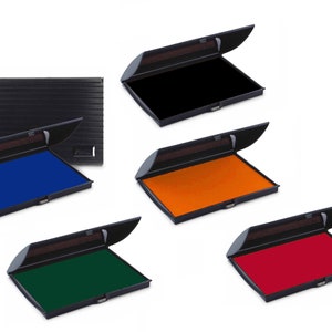May include: Five ink pads in different colors: black, blue, orange, green, and red. The ink pads are open and show the ink color. The ink pads are made of black plastic.