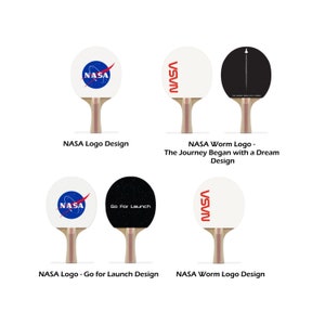 May include: Four different designs for a ping pong paddle featuring the NASA logo. The designs include the classic NASA logo, the NASA worm logo, the NASA worm logo with the text "The Journey Began with a Dream", and the NASA logo with the text "Go For Launch".